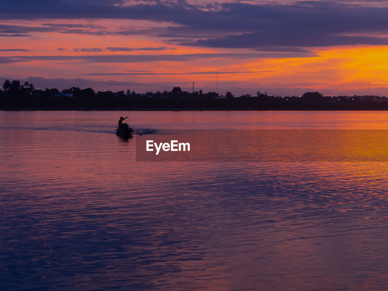 Silhouette person in sea against sky during sunset