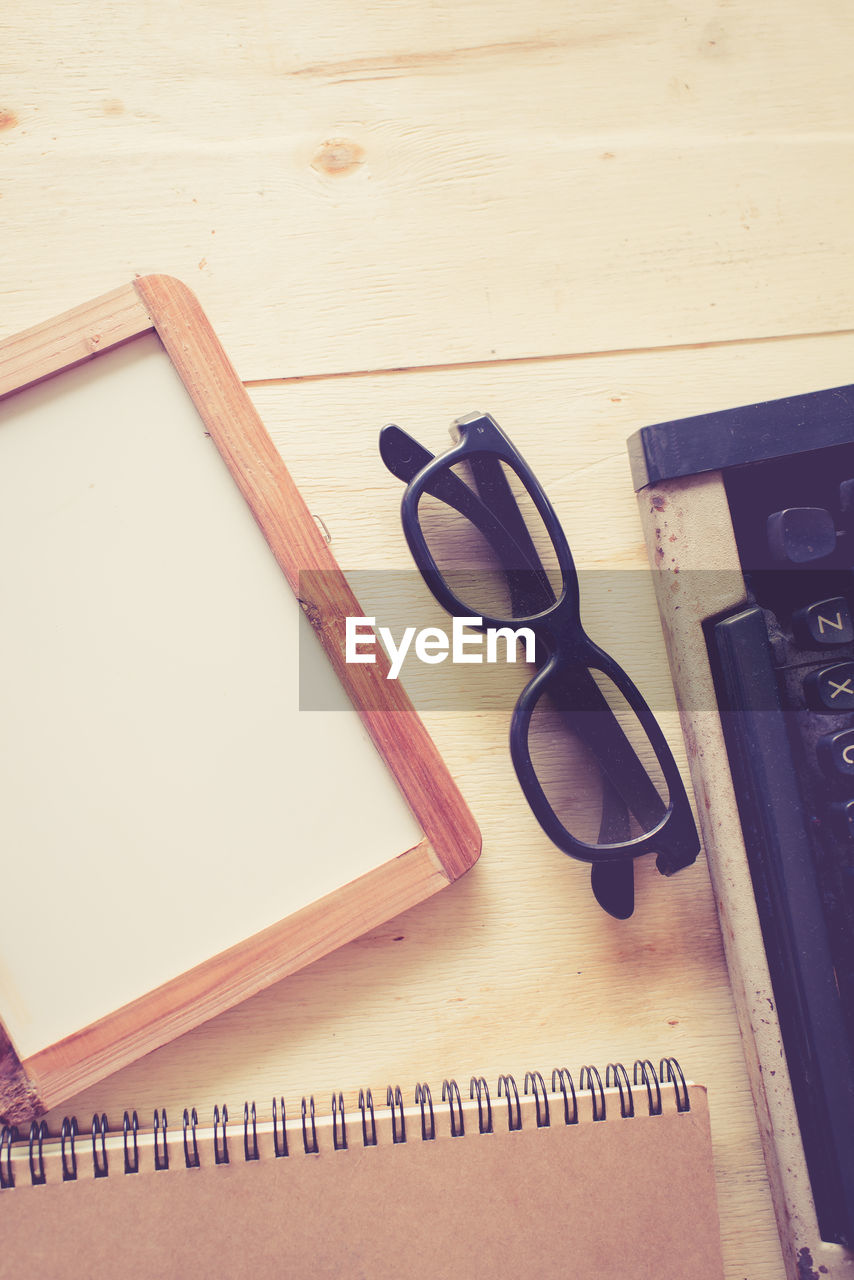 Directly above shot of typewriter with book and eyeglasses on table