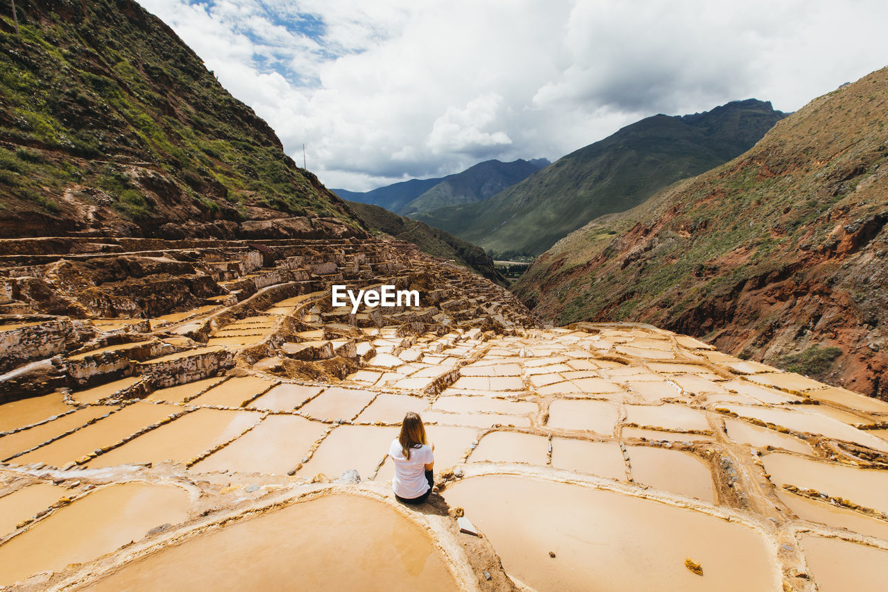Young woman is sitting near the famous salt mines in peru