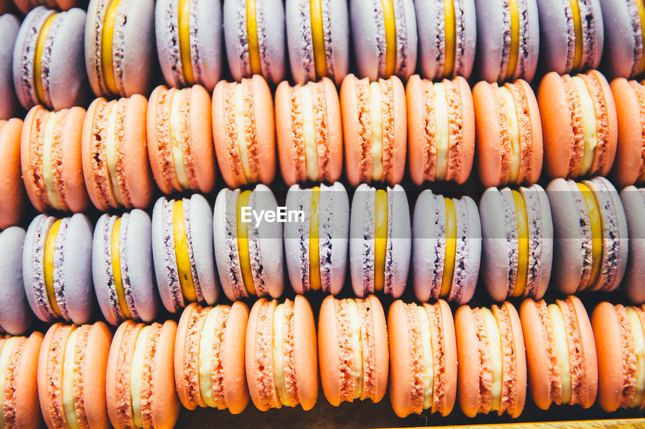 Macaroons of purple and coral color with yellow cream in a box close-up