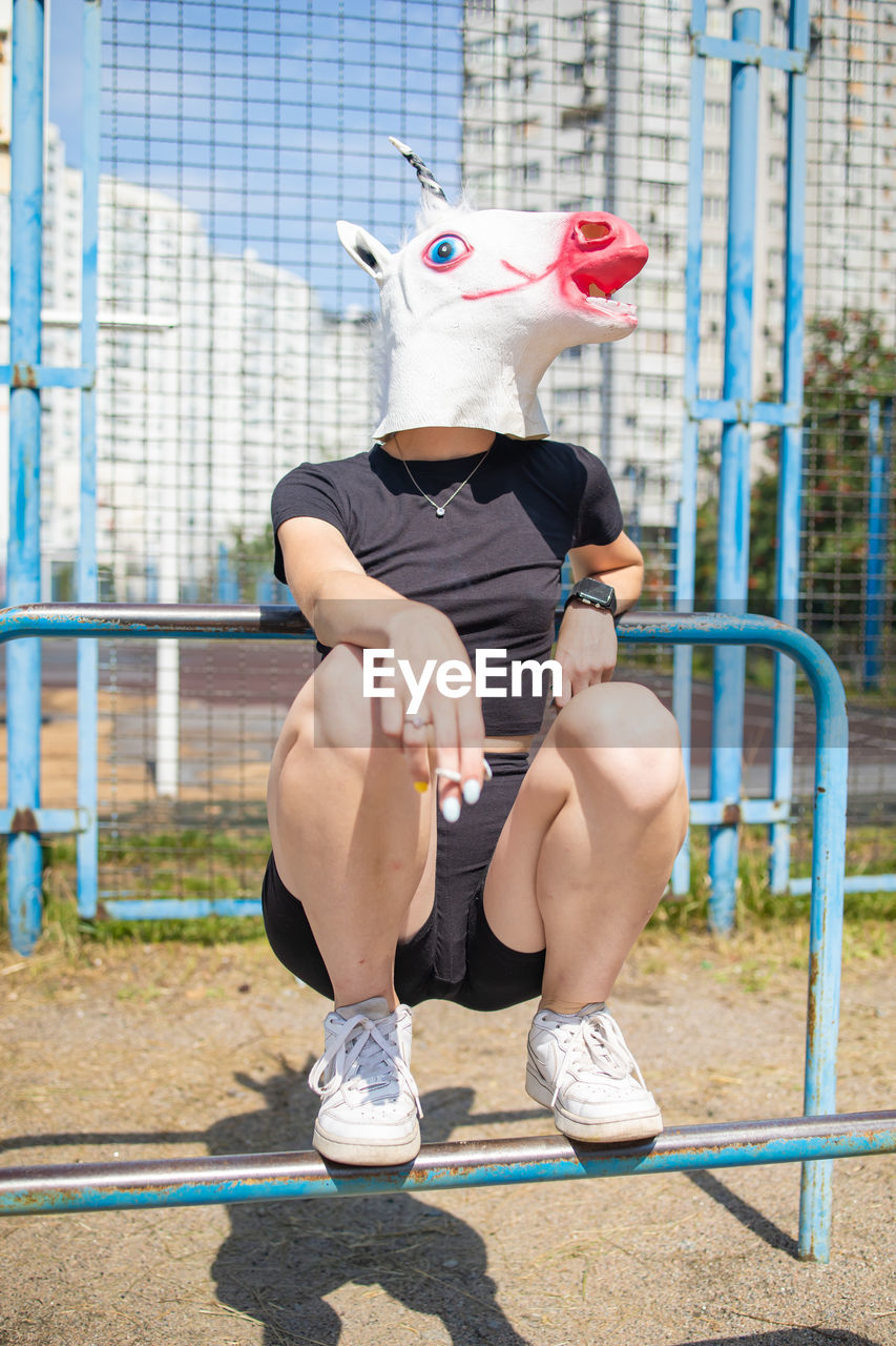  woman wear unicorn head sitting on playground