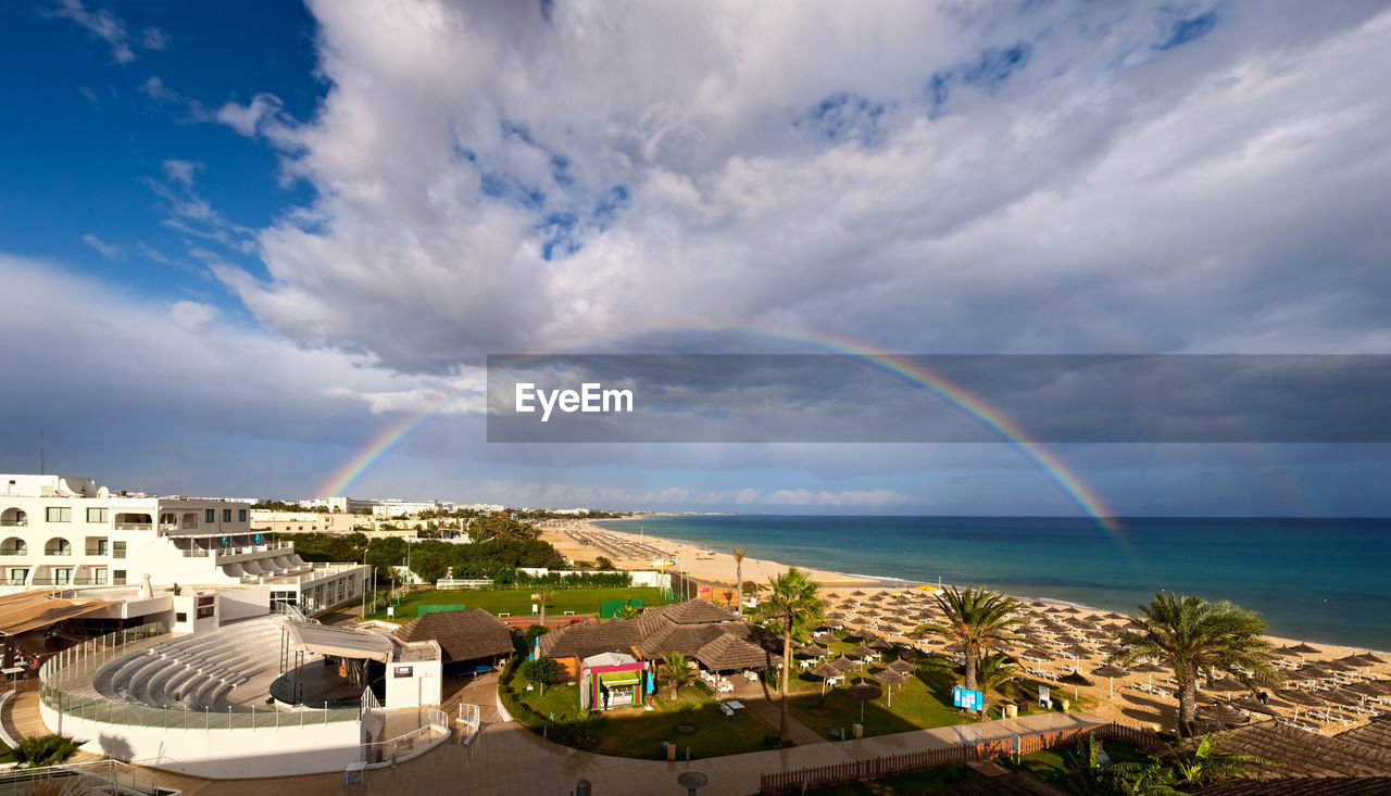 SCENIC VIEW OF RAINBOW OVER SEA AND BUILDINGS