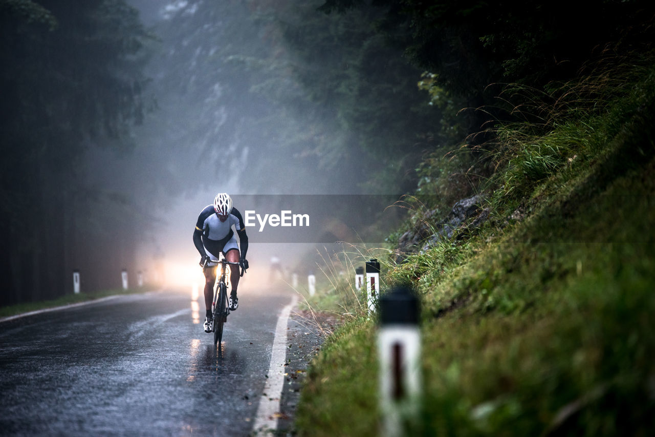 FULL LENGTH OF MAN RIDING BICYCLE ON ROAD