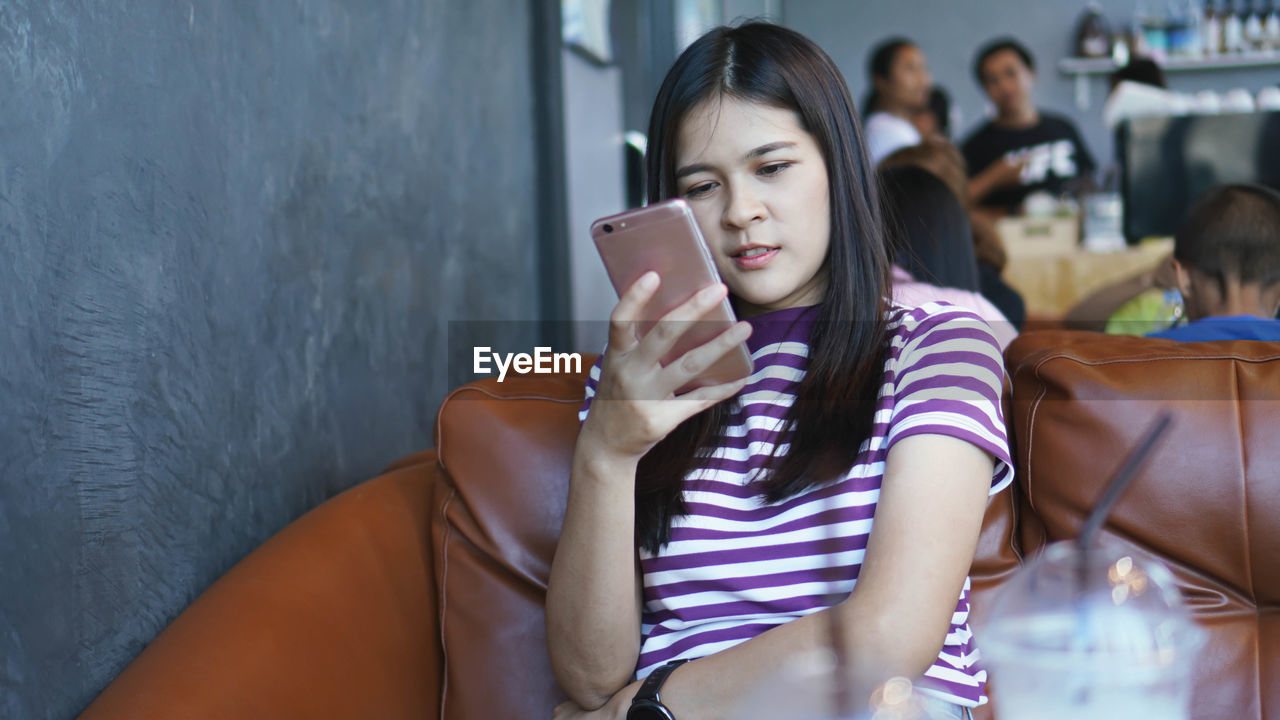 Young woman using smart phone sitting at cafe 