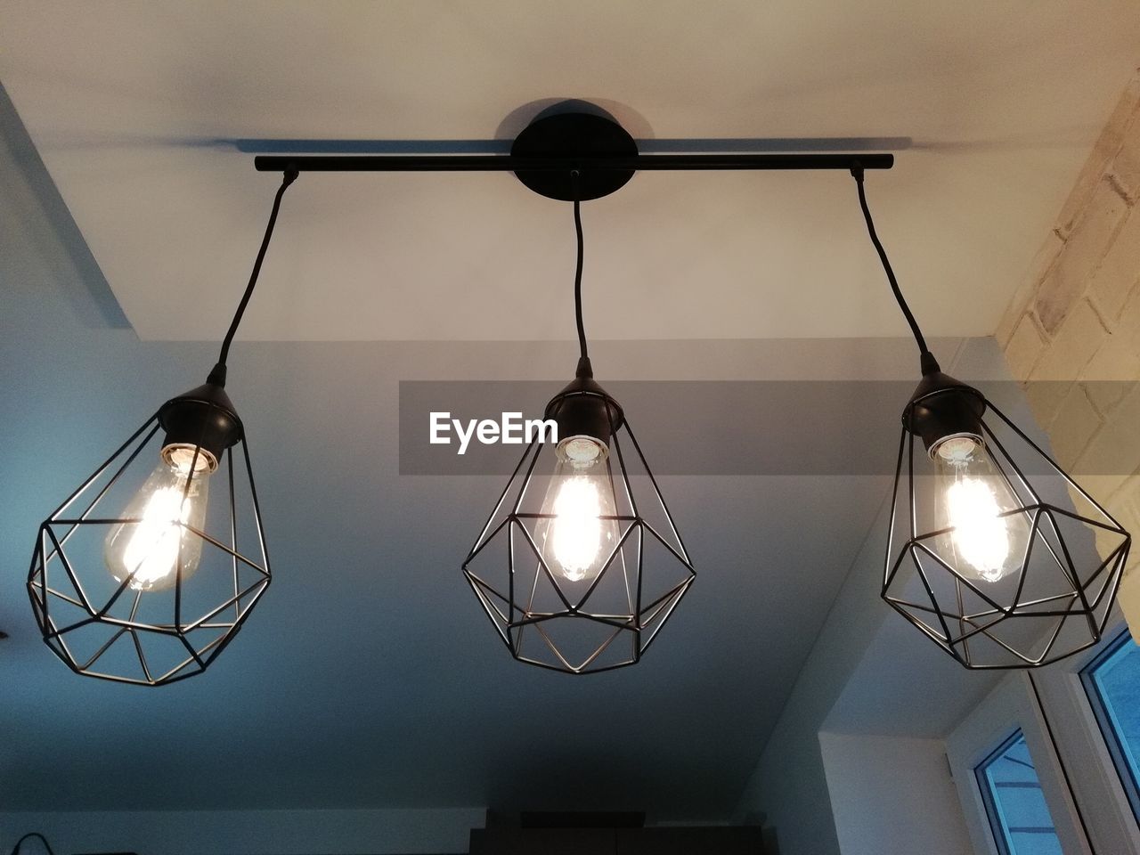 LOW ANGLE VIEW OF ILLUMINATED PENDANT LIGHTS HANGING FROM CEILING