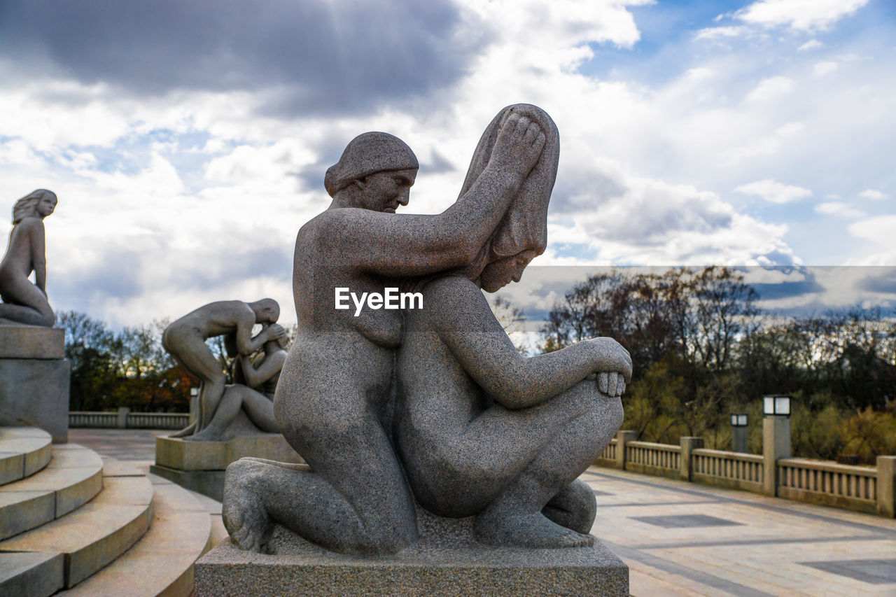 Statues on staircase against cloudy sky