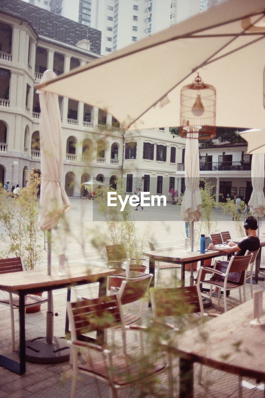 Man listening to music while sitting on chair at cafe in city