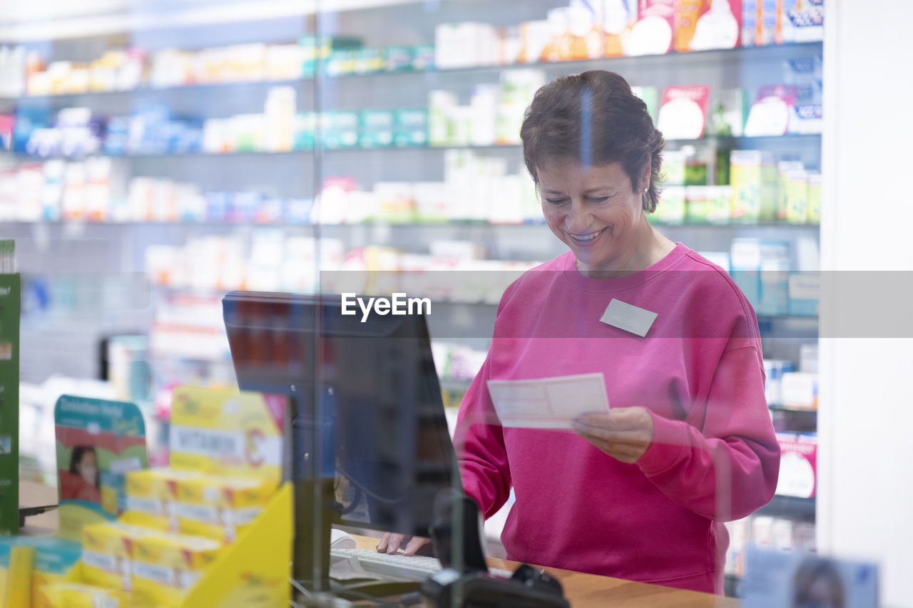 Happy pharmacist examining prescription at medical store