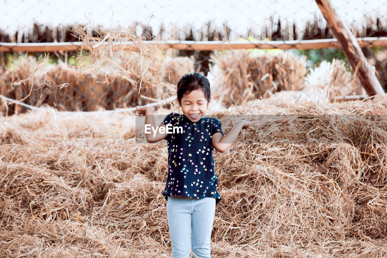 Cheerful girl playing on hay 