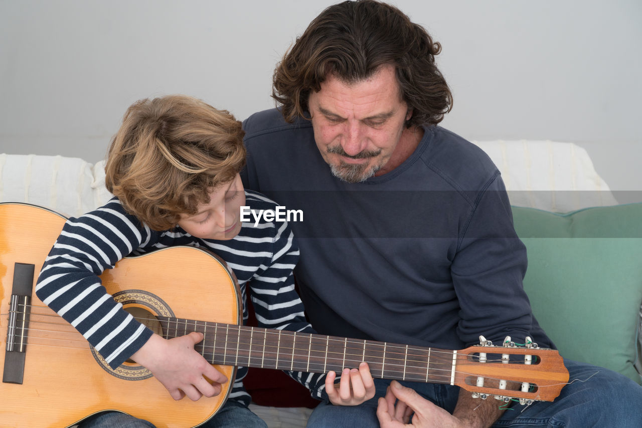 Father teaching guitar to son