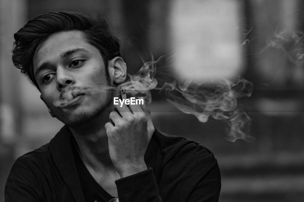 Portrait of young man smoking cigarette