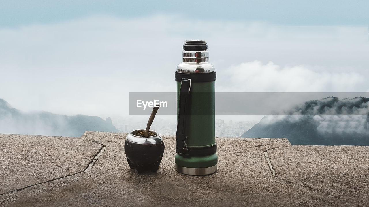 Close-up of water bottle on mountain against sky