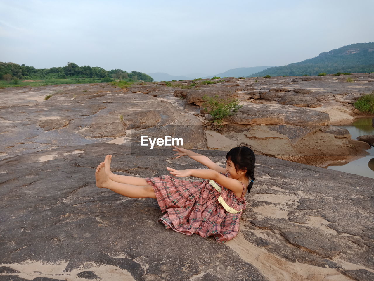 Girl sitting on rock against sky