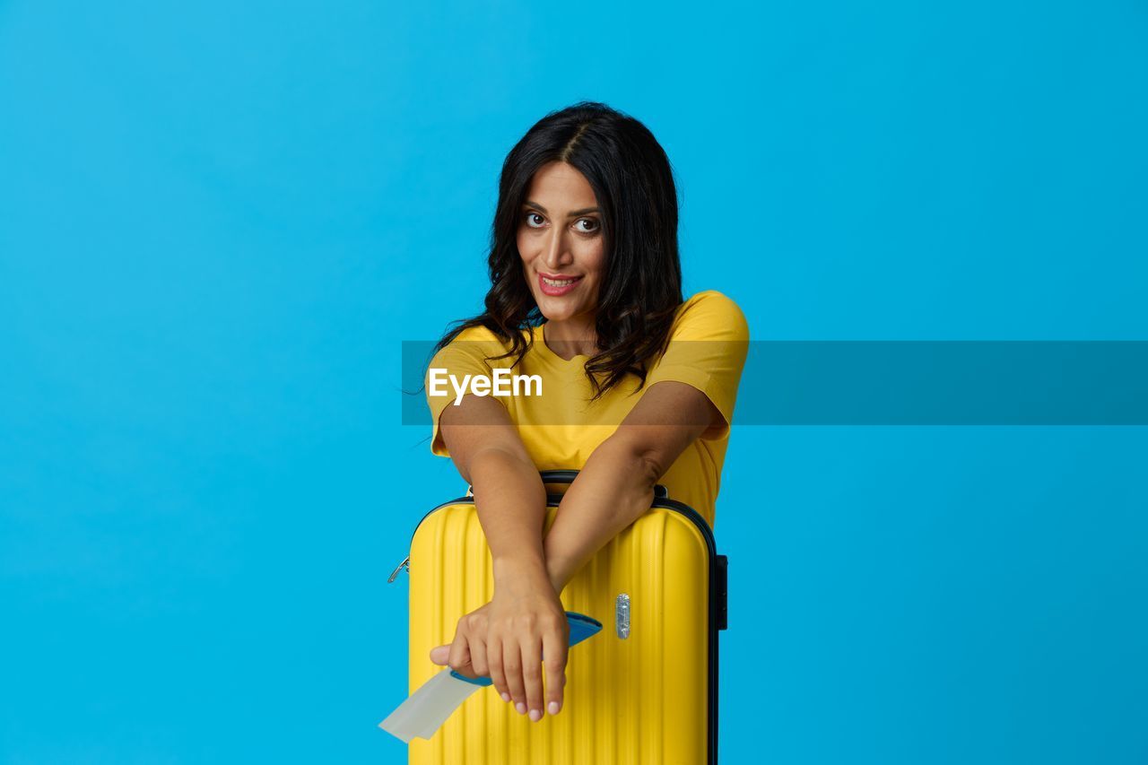 portrait of young woman sitting on blue background