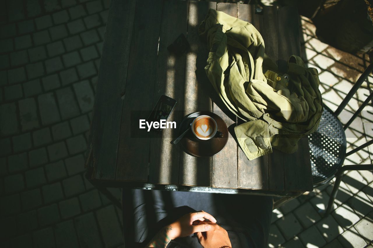 High angle view of man with coffee and smart phone sitting at table