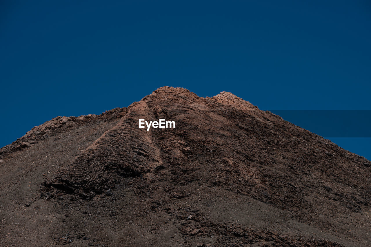 LOW ANGLE VIEW OF ROCKY MOUNTAIN AGAINST BLUE SKY