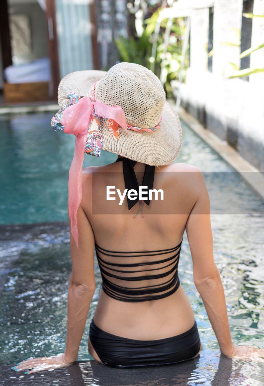 Rear view of woman standing in swimming pool