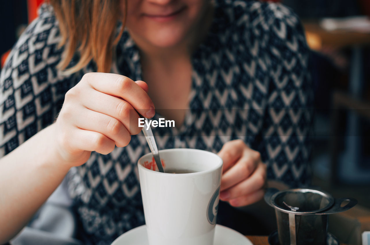 Midsection of woman preparing tea at cafe