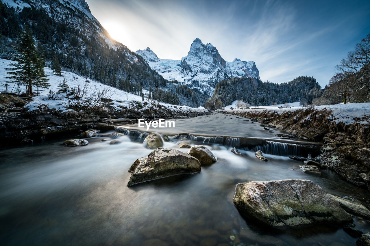 SCENIC VIEW OF STREAM BY SNOWCAPPED MOUNTAIN AGAINST SKY