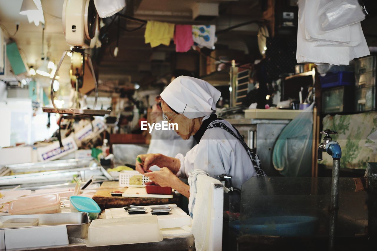 Side view of senior woman working in factory