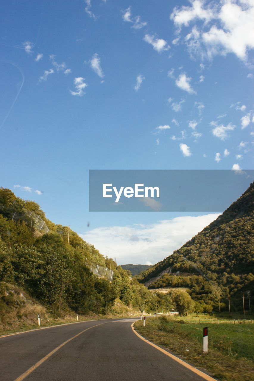 Road by mountains against sky