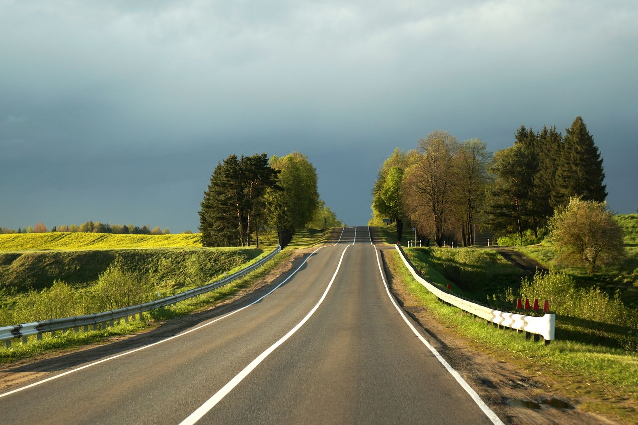 road, sky, transportation, cloud, plant, highway, tree, the way forward, nature, landscape, environment, land, no people, symbol, beauty in nature, scenics - nature, road marking, diminishing perspective, non-urban scene, marking, vanishing point, tranquility, rural area, infrastructure, travel, rural scene, grass, green, lane, country road, outdoors, tranquil scene, freeway, sign, morning, day, street, forest, travel destinations, asphalt, overcast, horizon, dividing line, remote, hill, empty road, road surface, idyllic