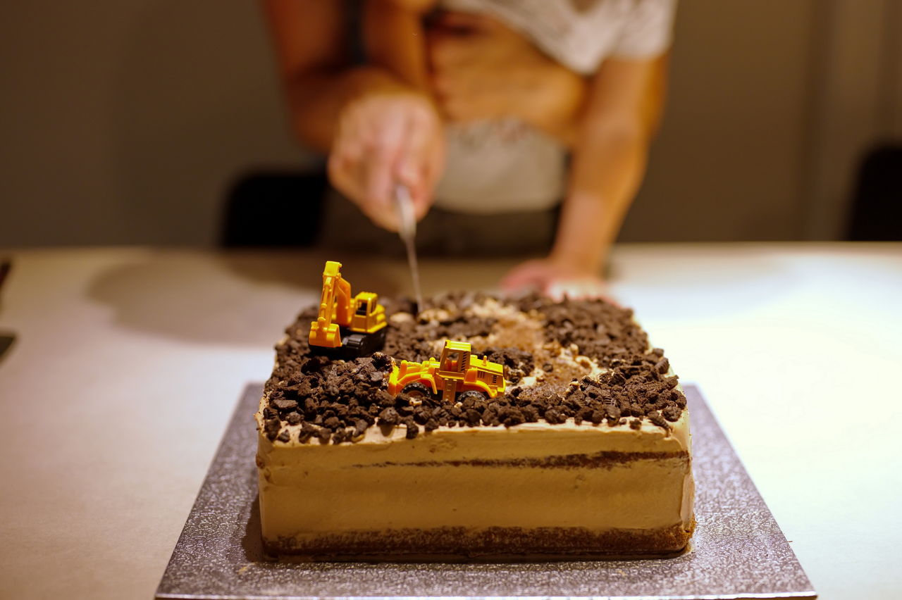 Midsection of mother and son cutting birthday cake