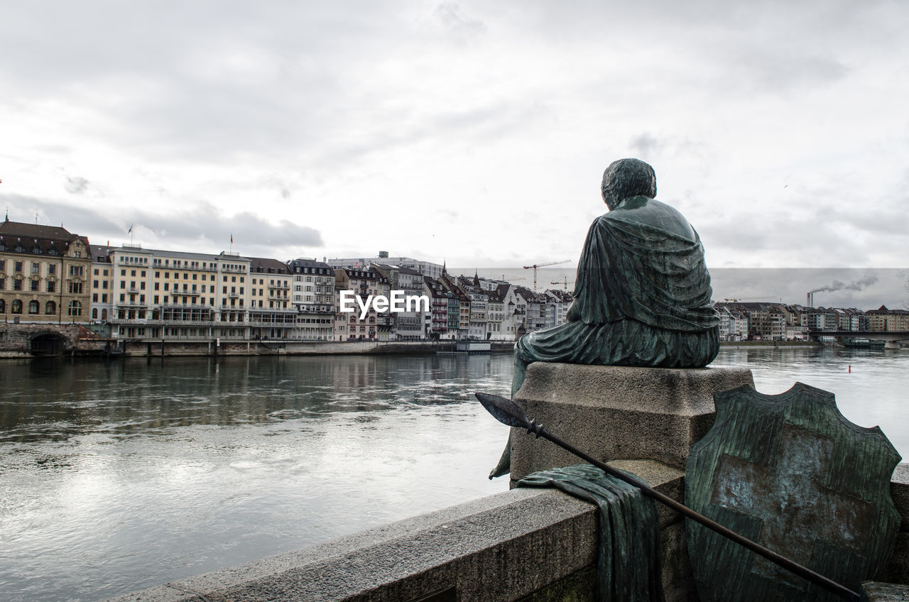 REAR VIEW OF STATUE ON RIVER AGAINST BUILDINGS