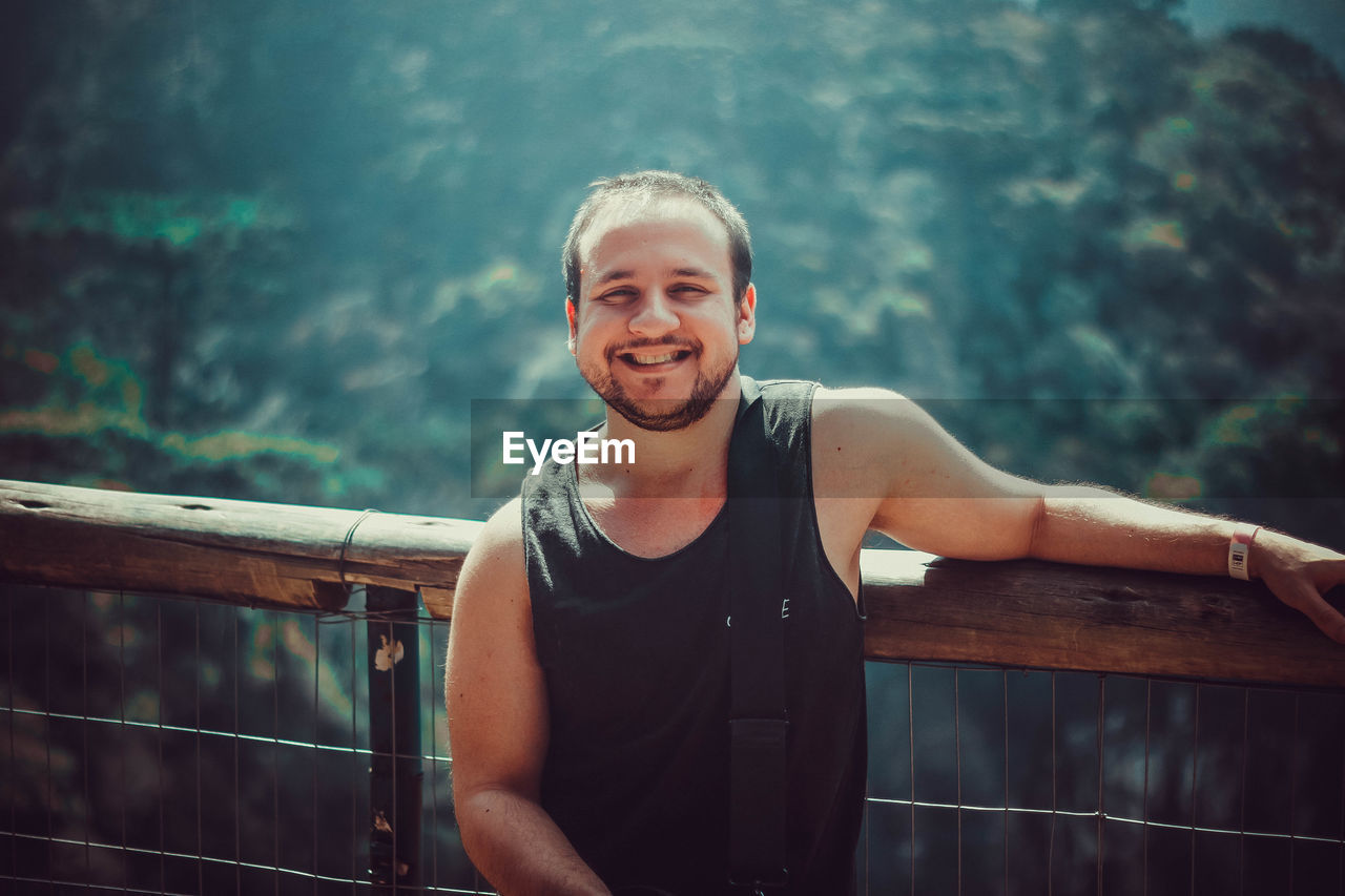 Portrait of smiling young man against railing