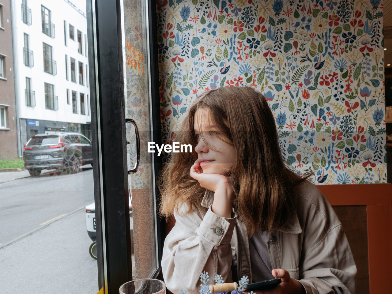 Portrait of a young girl sitting at the window of the cafe