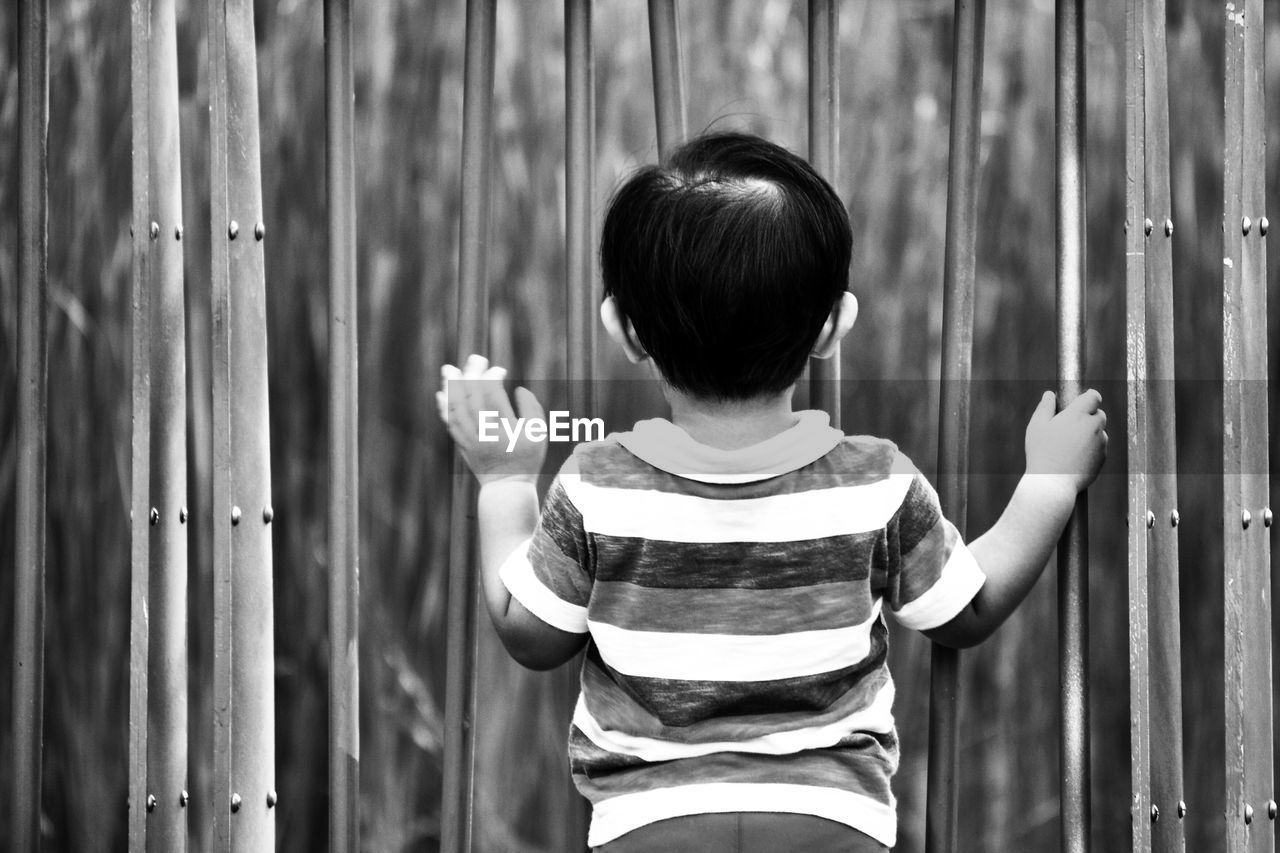 Rear view of boy standing by gate