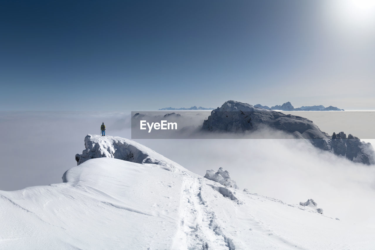 Person standing on snowcapped mountain against sky