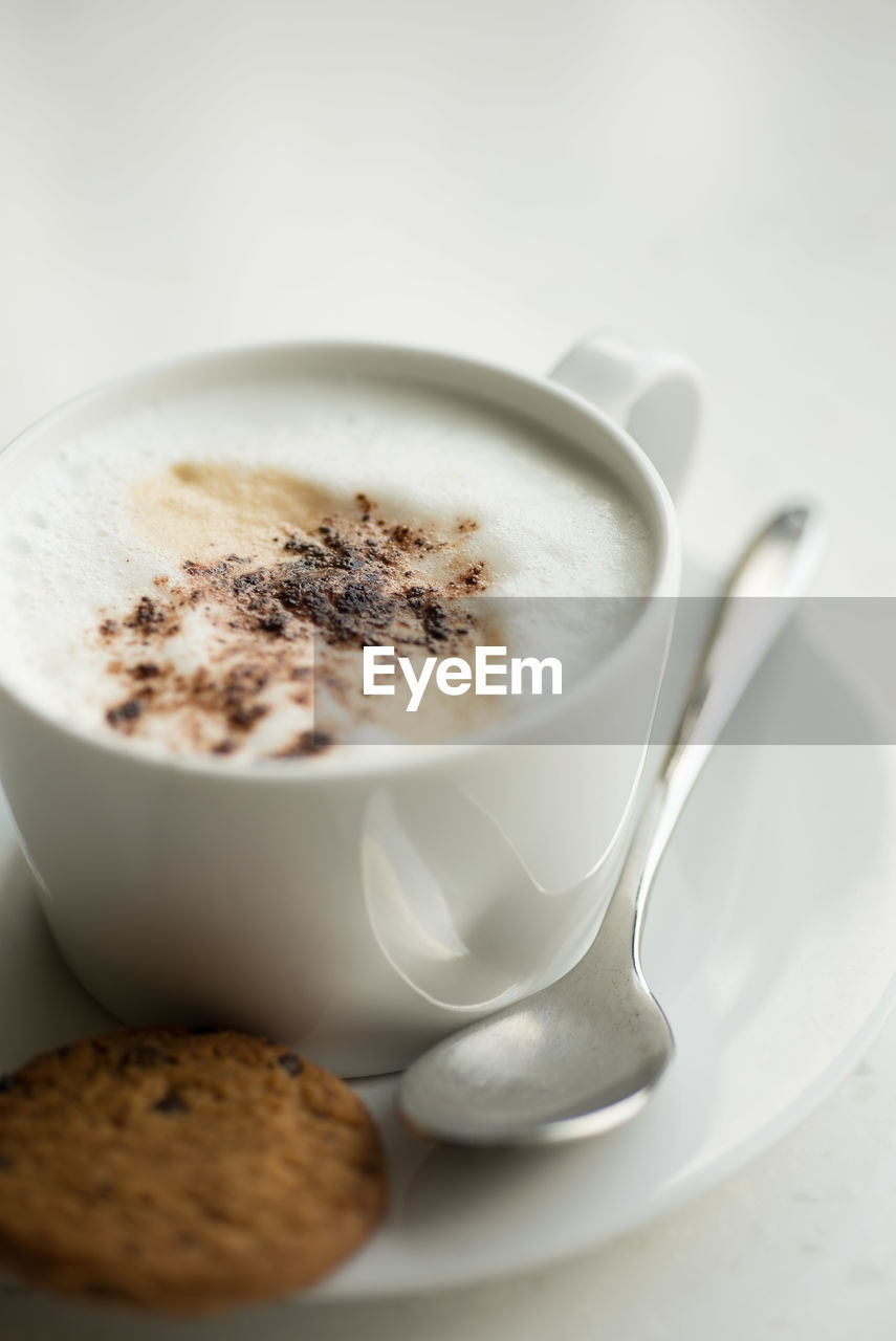 Close-up of coffee with cookie on table over white background