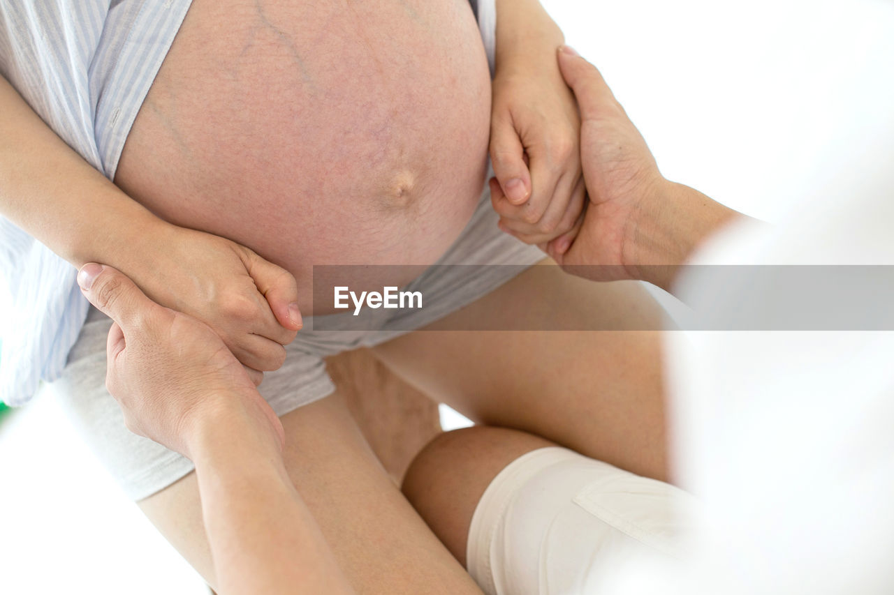 Midsection of man holding pregnant woman hands