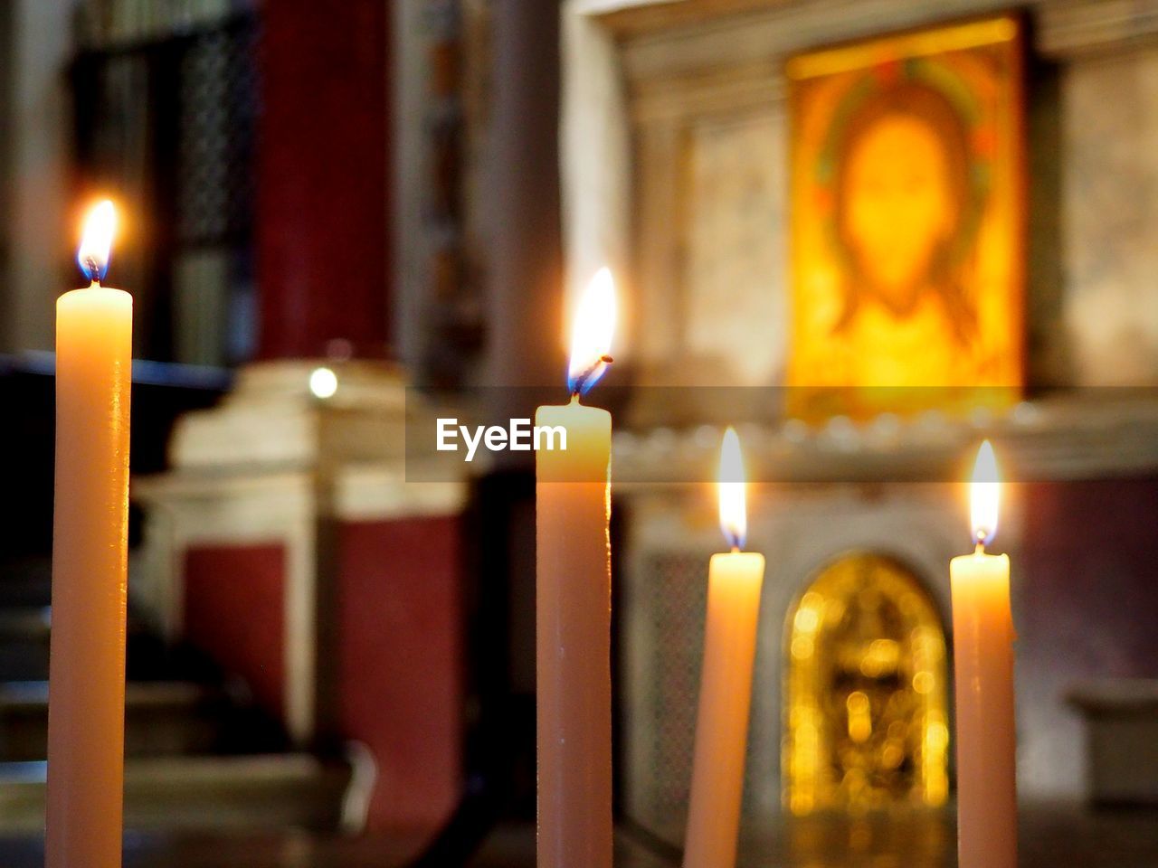 CLOSE-UP OF LIT CANDLES IN ILLUMINATED TEMPLE