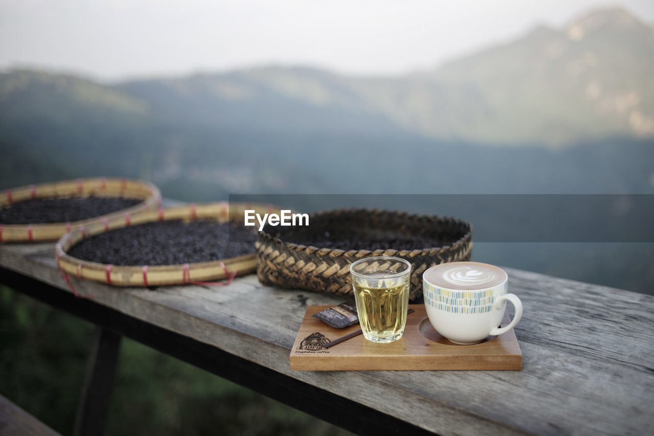 CLOSE-UP OF COFFEE CUP ON TABLE AGAINST BLURRED BACKGROUND