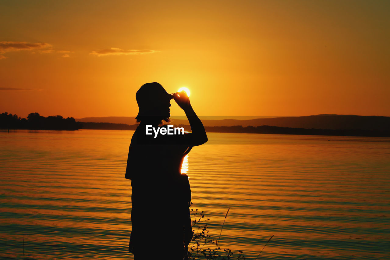 REAR VIEW OF SILHOUETTE MAN LOOKING AT SEA AGAINST SKY