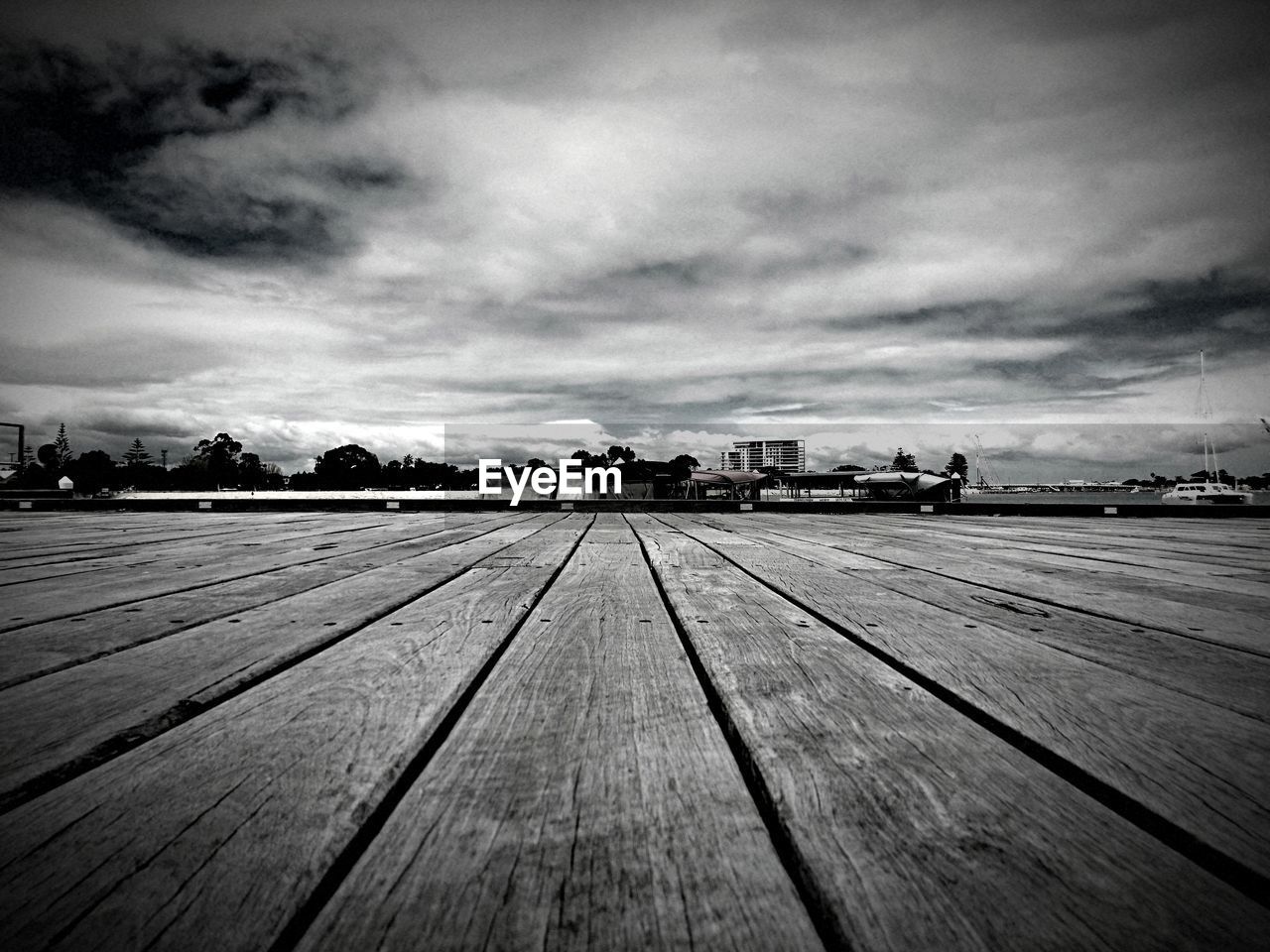 VIEW OF EMPTY BOARDWALK AGAINST CLOUDY SKY