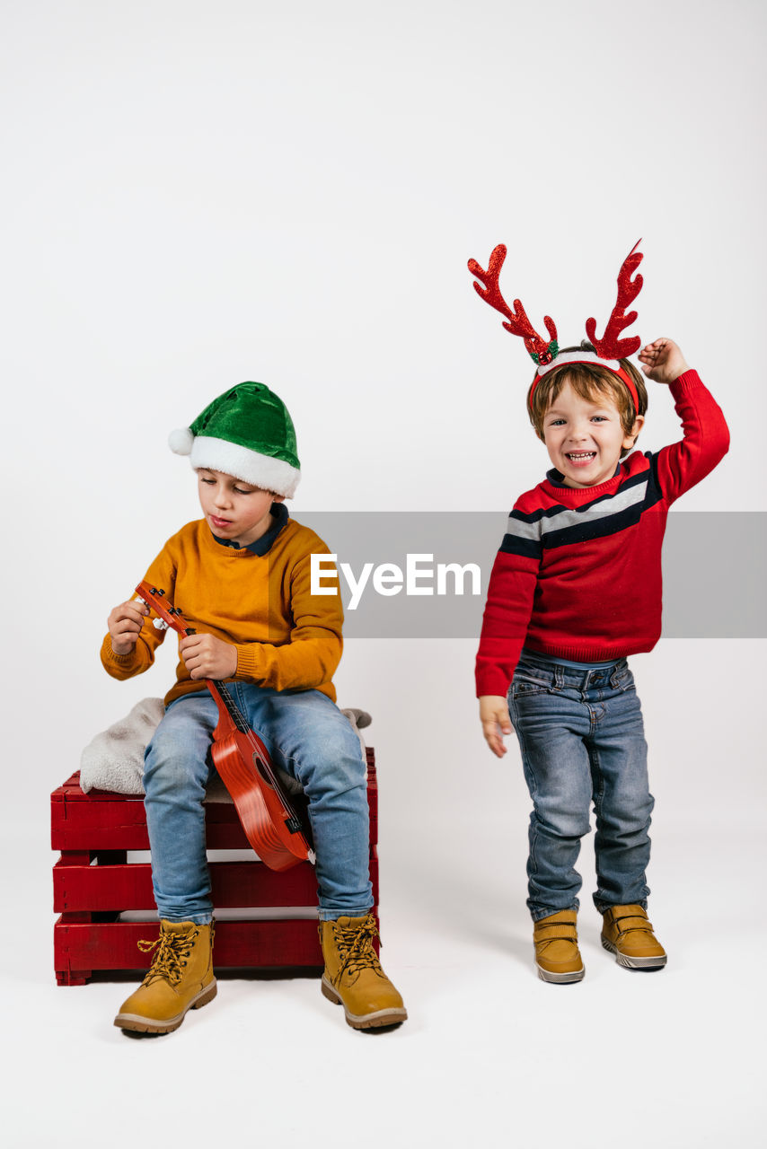 child, childhood, men, full length, white background, studio shot, two people, clothing, fun, indoors, person, footwear, emotion, portrait, dressing up, happiness, costume, smiling, friendship, front view, cute, red, togetherness, cartoon, looking at camera, toy, headwear, hat, cut out, family, celebration, standing