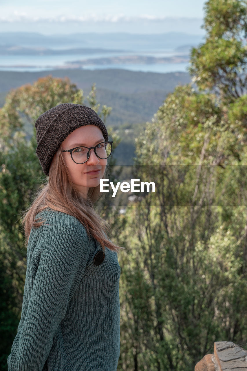 Portrait of smiling woman standing against trees