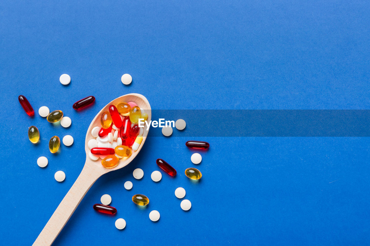 blue, blue background, colored background, pill, studio shot, dose, large group of objects, indoors, high angle view, no people, variation, medicine, food and drink, multi colored, food, capsule, healthcare and medicine, copy space, directly above, still life, vitamin, table, nutritional supplement