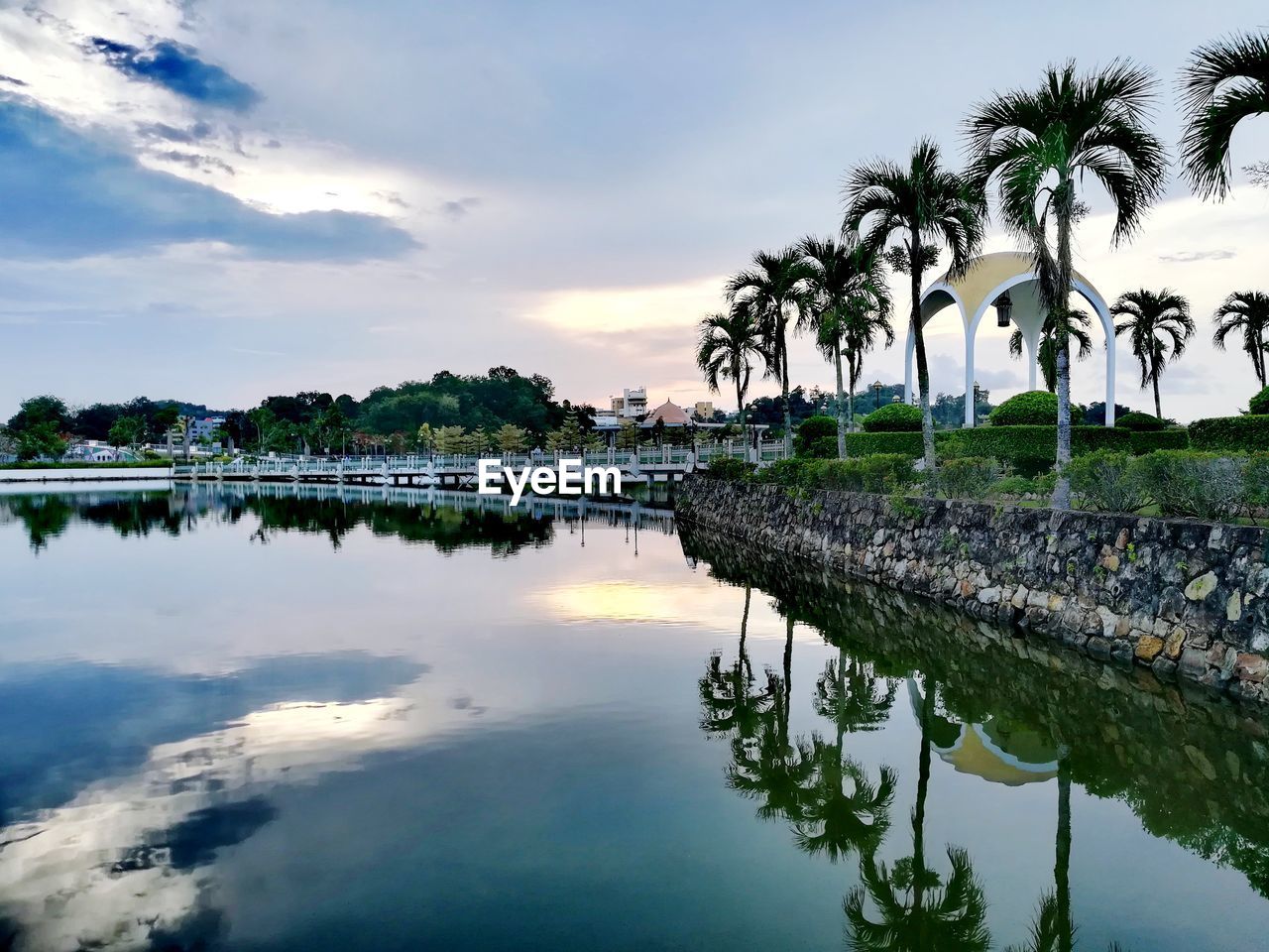 REFLECTION OF PALM TREES IN SWIMMING POOL AGAINST LAKE