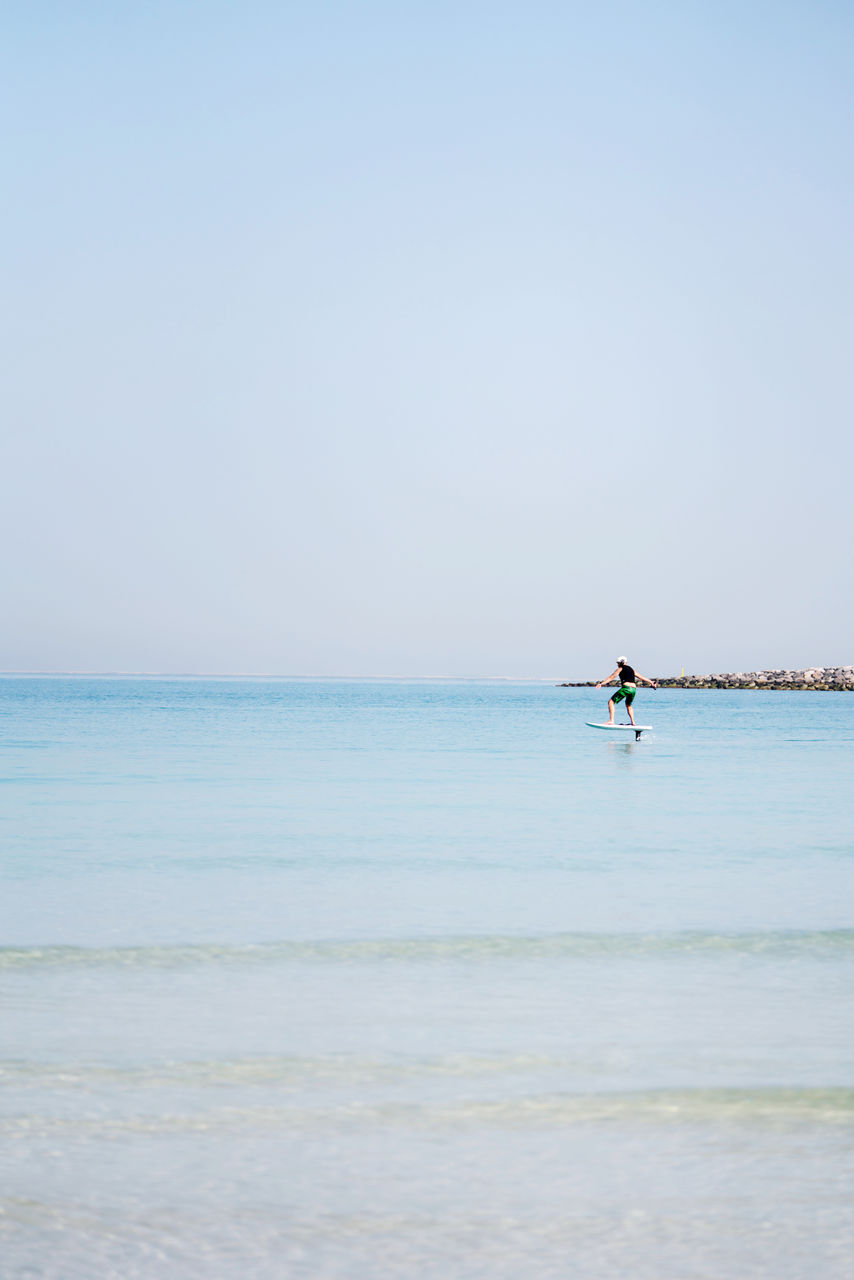 Man doing e foiling around people paddle boarding