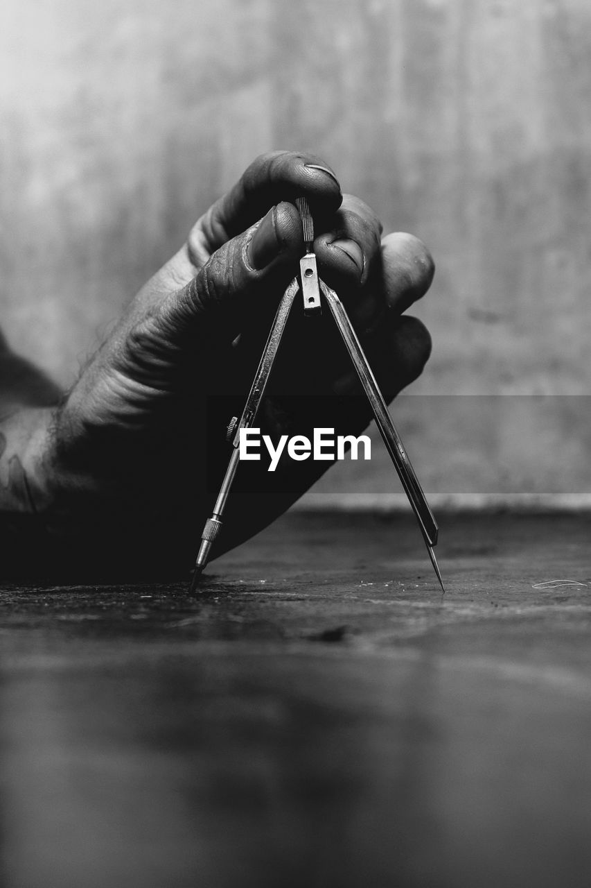 Cropped hand of man holding equipment on table