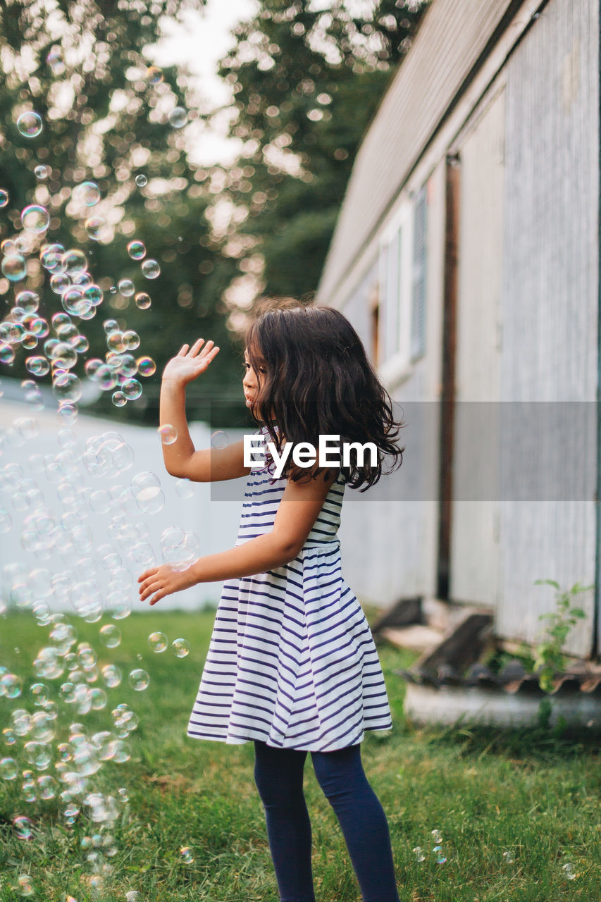 Diverse mixed race pre school age girl at home having fun playing with bubbles 