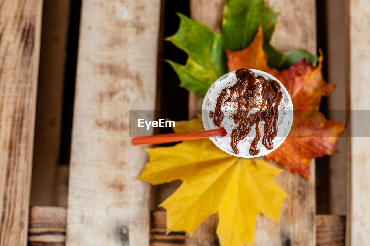 Autumn composition still life. cup of coffee latte with cocktail straw and autumn colored leaves on