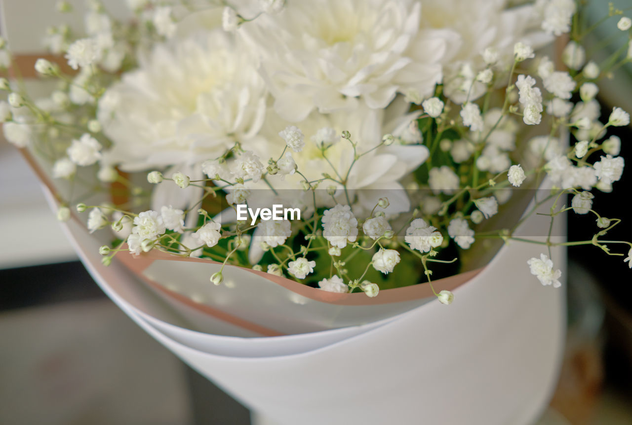 Bouquet of white chrysanthemums and gypsophila wrapped in craft paper. 