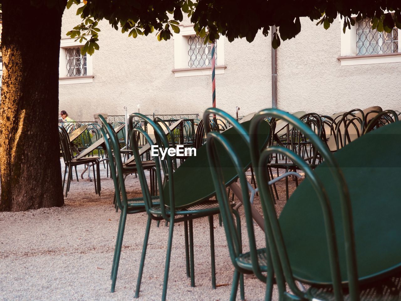 Empty chairs and tables at sidewalk cafe by building