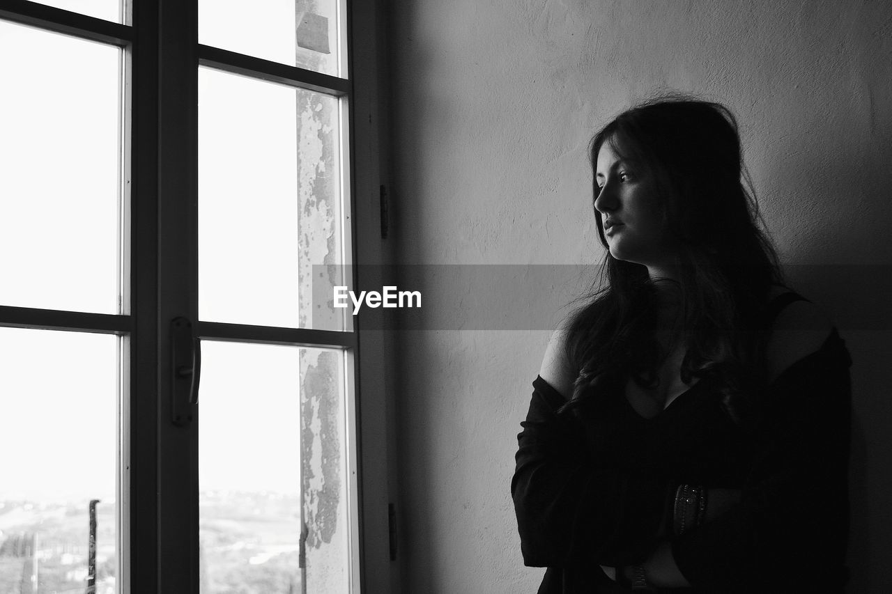 Woman looking away while standing at home