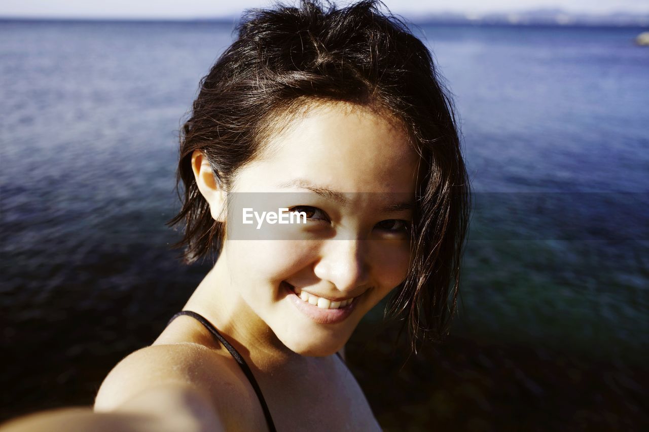Portrait of a smiling young woman against calm sea